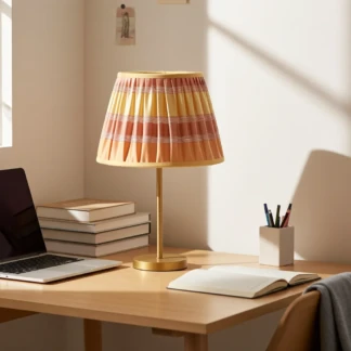 Paralume artigianale a righe gialle e arancioni su lampada da scrivania in un ufficio moderno e luminoso.