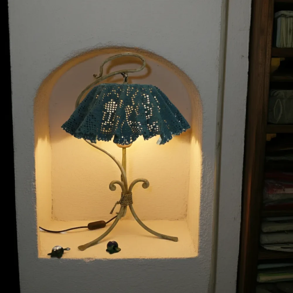 Paralume in centrino ad uncinetto per lampada artigianale Paralume artigianale realizzato con centrino ad uncinetto di colore blu-verde, montato su lampada da tavolo in ferro battuto.