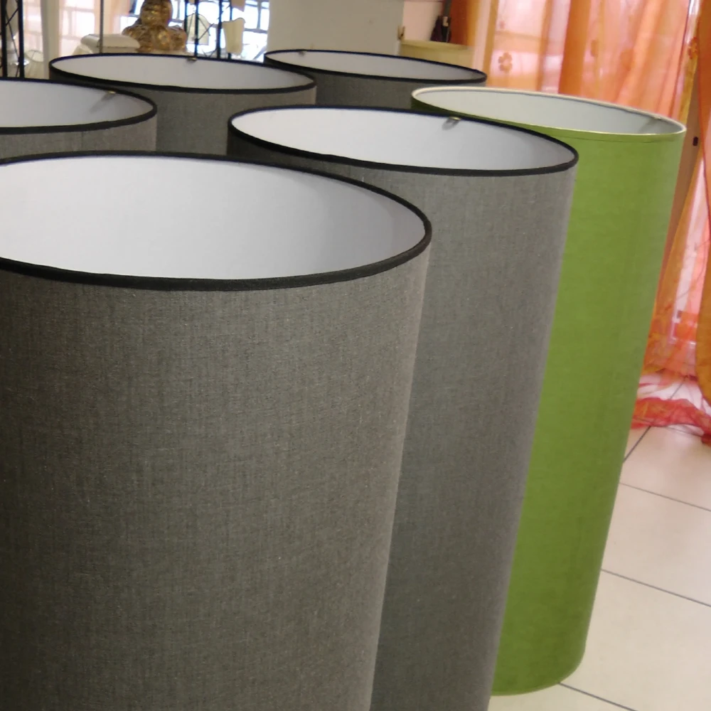 Paralumi Cilindrici Alti in Tessuto Grigio e Verde Acido Gruppo di paralumi cilindrici di grandi dimensioni, rivestiti in tessuto nei colori grigio e verde acido, in attesa di essere montati.