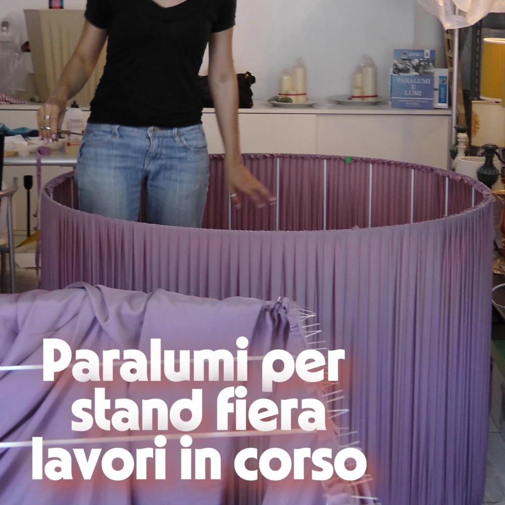 Maxi Paralumi in Tessuto Lilla Arricciato per Allestimenti Fiere Paralume cilindrico gigante in lavorazione, in tessuto lilla arricciato, destinato all'illuminazione di stand fieristici.