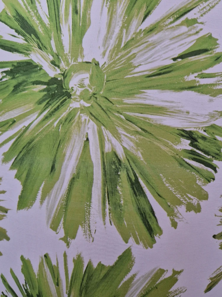 Dettaglio ravvicinato della stoffa a fiori verdi effetto pennellata utilizzata per paralumi cilindrici artigianali.