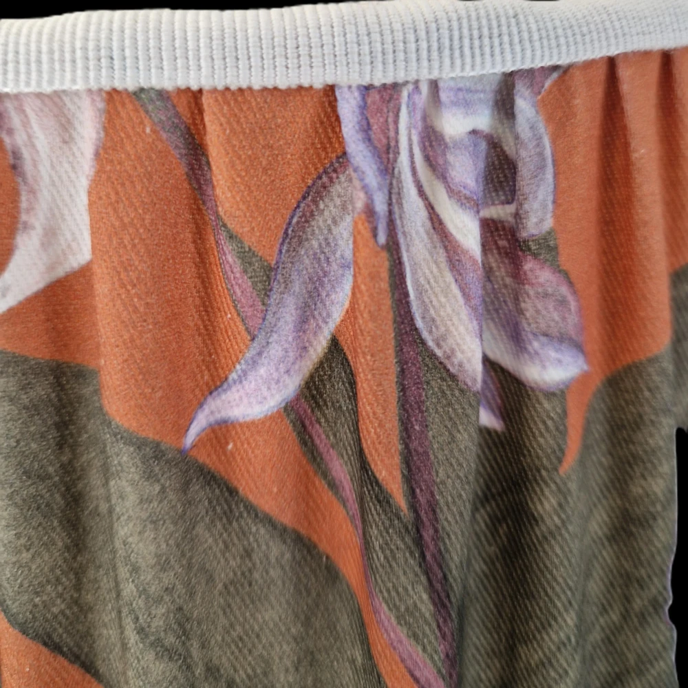 Dettaglio tessuto botanico a fiori con orchidee su sfondo arancio e finitura passamaneria gros grain di un paralume artigianale - Paralumi e Lumi Prato